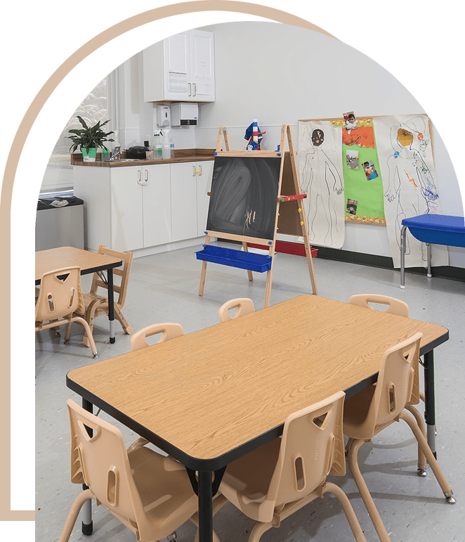 A classroom with tables and chairs, a chalkboard and an easel.